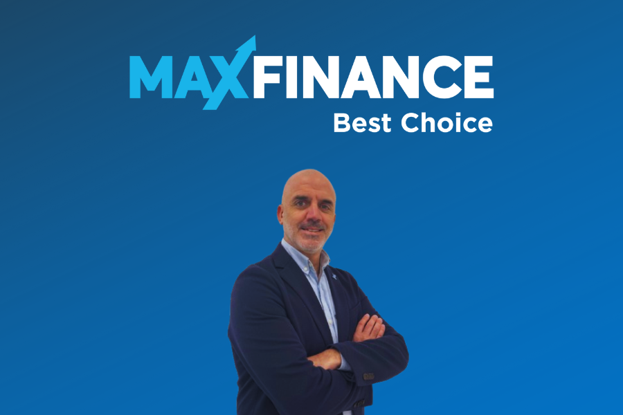 Homem de fato azul escuro e camisa branca, de braços cruzados, sorridente, em frente a um fundo azul com o logótipo “MAXFINANCE Best Choice” no topo